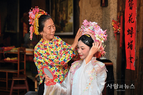 A tourist (right) is wearing flowery headwear at Xunpu Village of Quanzhou City, southeast China
